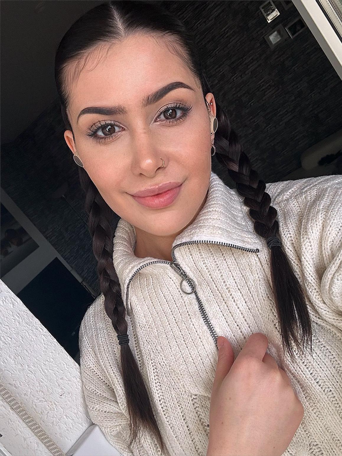 Back of a man at a concert. Hes wearing a beanie hat and a baggy denim jacket with studs. Photo with a purple hue